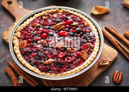 Autumn Pie on rustic background close up. Homemade seasonal pastry - berries and pecan pie or tart for Thanksgiving and autumn holidays. Stock Photo