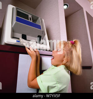 Child getting money from ATM Stock Photo