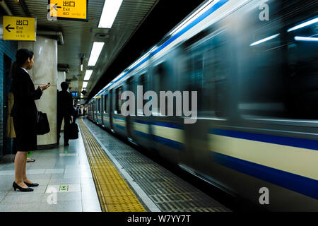Woman waiting for train in Tokyo underground, Japan Stock Photo