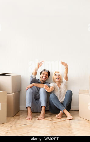 Excited Couple Sitting On Floor Discussing Future Interior Design Stock Photo