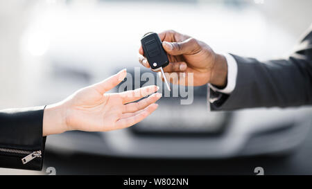 Car sale. Dealer giving key to new owner Stock Photo