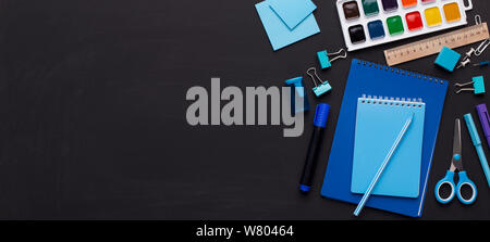 Blue colored school stationery on black board with copy space Stock Photo