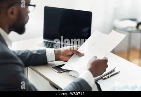 African entrepreneur reading financial reports, working in modern office Stock Photo