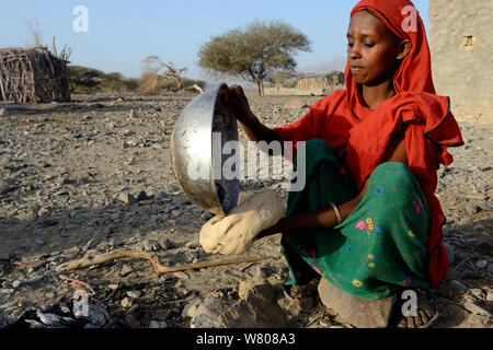 Afar tribe woman baking bread with a hot stone, Malab-Dei village, Danakil depression, Afar region, Ethiopia, March 2015. Stock Photo