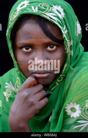 Head portrait of young Afar tribe woman with facial tattoo / skin scarifications and head scarf, Malab-Dei village, Danakil depression, Afar region, Ethiopia, March 2015. Stock Photo