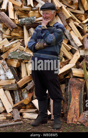 Subsistence farmer standing in front of log pile, Musteika Village, Lithuania, May 2015. Stock Photo