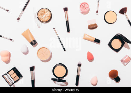 Creative makeup background of cosmetic products on white table in bright light with visible shadows, flat lay pattern. Stock Photo