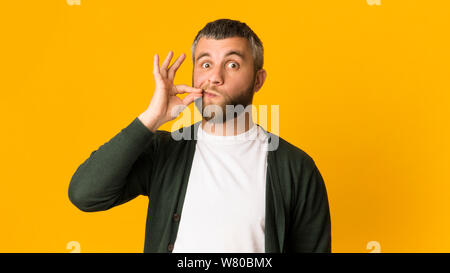 Handsome caucasian man zipping his mouth with gesture Stock Photo
