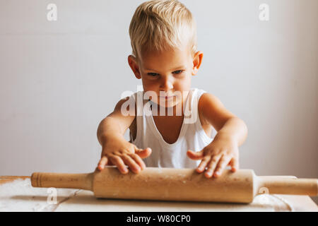 Funny happy chef boy cooking pizza at home at the table Stock Photo
