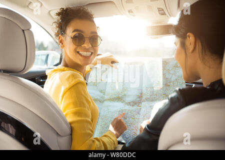 Friends travel by car. Girls looking at map, building route Stock Photo