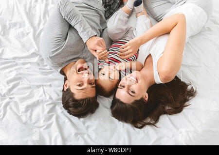 Young man, woman and baby cuddling in bed together Stock Photo