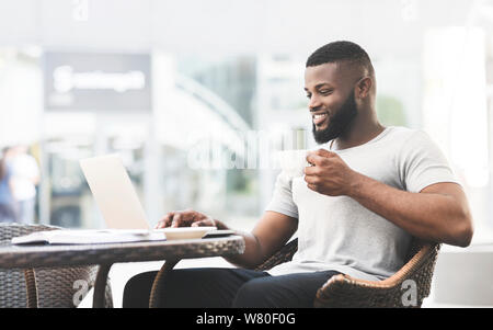 African american man having lunch time in cafe and using laptop Stock Photo