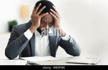 Afro businessman suffering from headache, touching his temple Stock Photo