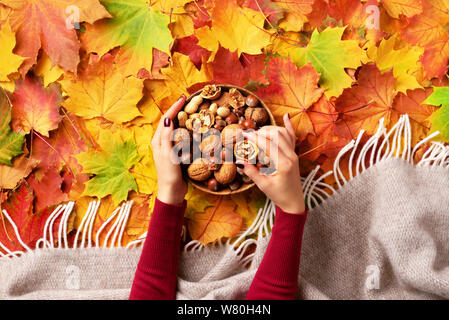 Autumn flat lay. Woman hands holding wooden bowl with mixed nuts. Healthy food and snack. Vegan, vegetarian, raw meal concept. Walnut, almonds, hazeln Stock Photo