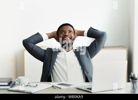 Dreamy african american businessman leaning back in office Stock Photo