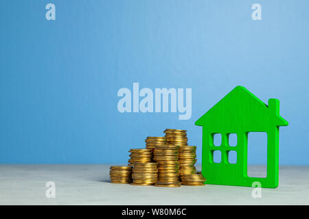 House and stack of coins. The concept of buying home or insurance. Blue background. Copy space for text Stock Photo
