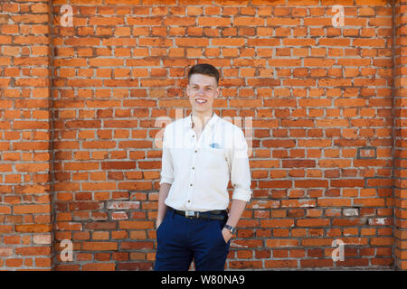 Portrait of a casually dressed young businessman standing against a brick wall Stock Photo