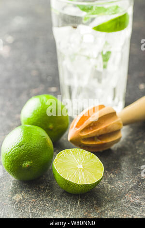 Wooden citrus squeezer and green lime on old kitchen table. Stock Photo