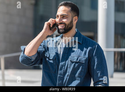 Young bearded businessman talking on his cellphone outdoors Stock Photo