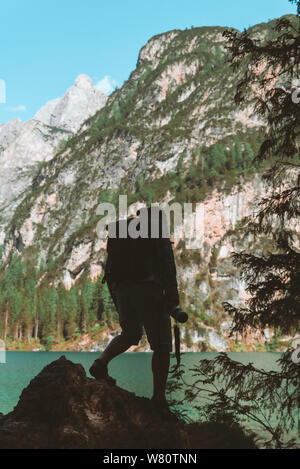 man climbing by rocks to shoot beautiful landscape of lake and mountains. photographer activities Stock Photo