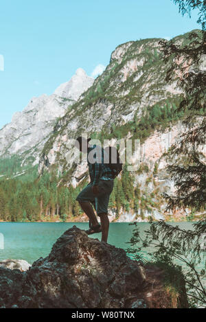 man climbing by rocks to shoot beautiful landscape of lake and mountains. photographer activities Stock Photo