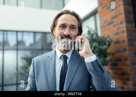 Businessman wearing stylish tie smiling while receiving phone call Stock Photo