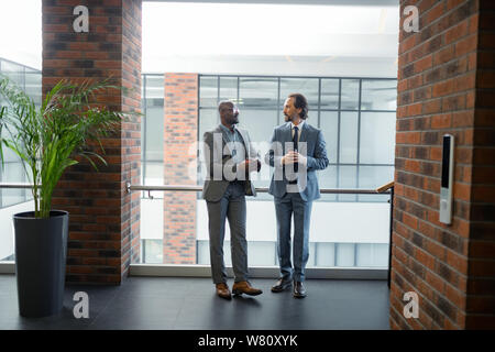 Two businessmen standing in spacious business center in the morning Stock Photo