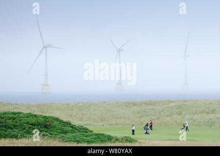 Donald Trump golf course showing wind farm turbines and golfers in the North Sea Balmedie Aberdeen Scotland UK Stock Photo