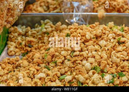 Pile of deep fried or bake pork snack, pork rind, pork scratching or pork crackling on the tray in a market. Stock Photo