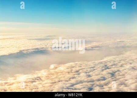 Beautiful scenic dramatic morning sunrise cloudscape aerial view from plane window. Gradient colored fluffy clouds during aircraft flight travel at Stock Photo