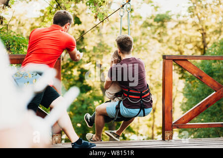 Back view of a ropeway worker pushing a couple over the ropeway ...