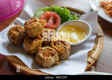 Hoi Jo, Crab jujube or Deep Fried Crab Meat Rolls, one of asian traditional food, serve on paper and basket with sweet dipping sauce on side. Stock Photo