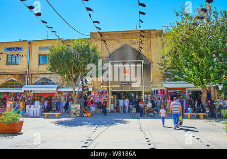 SHIRAZ, IRAN - OCTOBER 14, 2017: The urban scene in Zand walking street with a view on the portal of historical Vakil Bazaar, black Ashura flags, mark Stock Photo