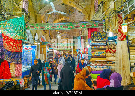 SHIRAZ, IRAN - OCTOBER 14, 2017: Textile section of Vakil Bazaar with many colorful fabrics in stalls, located on both sides of medieval covered alley Stock Photo