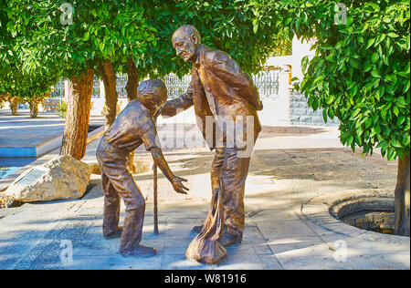 SHIRAZ, IRAN - OCTOBER 14, 2017: The bronze monument, depicting elderly  grandfather and his grandson, helping him to carry the bags, on October 14 in Stock Photo