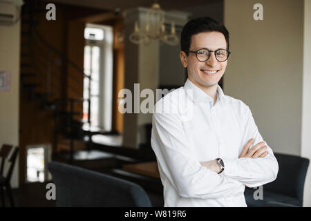 Portrait of confident elegant business man wearing glasses looking at camera smiling with crossed hands . Stock Photo