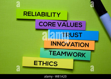 Reliability, Core Values, trust, Innovation, Teamwork, Ethics text on sticky notes isolated on green desk. Mechanism Strategy Concept Stock Photo