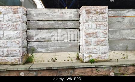 Brick fence with gray wooden shields, selective focus, copyspace Stock Photo