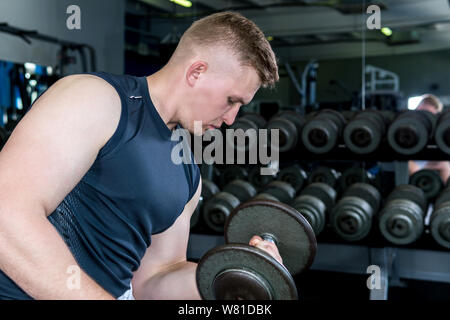 man doing dumbbell exercise for biceps at the gym Stock Photo