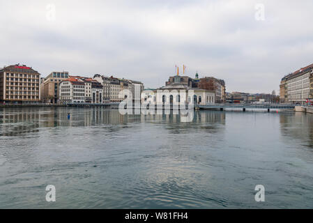 City view of waterside and pedestrian bridge cross Lake Geneva and Rhône rive, and background of Cité du Temps de Genève, Geneva's downtown and cloudy Stock Photo