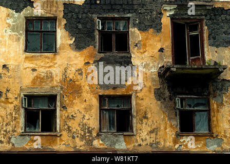 wall of an abandoned dilapidated old building with broken windows Stock Photo