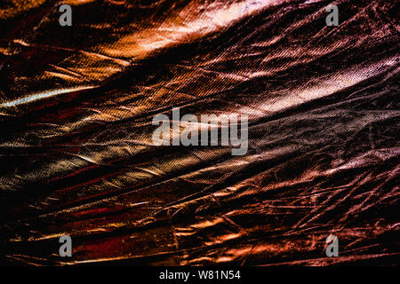 Textured copper foil background with shiny crumpled surface and gold reflects. Stock Photo