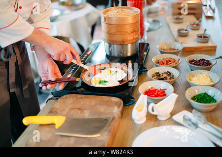 Breakfast. Scrambled eggs are cooked on an induction cooker in the restaurant. Stock Photo