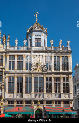 Brussels, Belgium - June 22, 2019: Beige stone facade and gable with statues on top of building named, Le Roy D’Espagne, with bar restaurant at ground Stock Photo