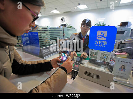 --FILE--A passenger uses the mobile app Alipay, the online payment service of Alibaba's Ant Financial, on her smartphone to scan the QR code to buy ti Stock Photo