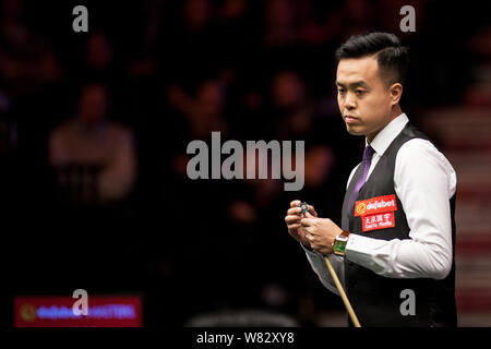 Marco Fu of Hong Kong chalks his cue as he considers a shot to Judd Trump of England in their first round match during the 2017 Dafabet Masters snooke Stock Photo