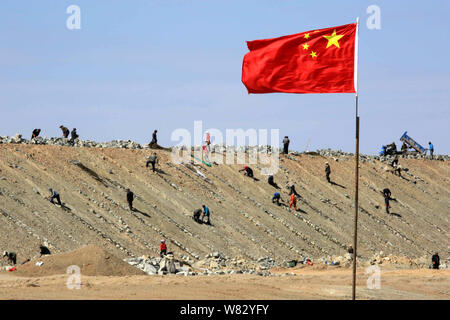 --FILE--A Chinese national flag flutters near a group of workers constructing the Ha'e (Hami-Ejina) Railway in Hami, northwest China's Xinjiang Uygur Stock Photo