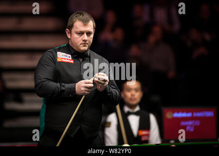 Mark Allen of Northern Ireland chalks his cue as he considers a shot to Marco Fu of Hong Kong in their quarterfinal match during the 2017 Dafabet Mast Stock Photo