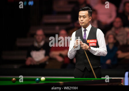 Marco Fu of Hong Kong chalks his cue as he considers a shot to Judd Trump of England in their first round match during the 2017 Dafabet Masters snooke Stock Photo