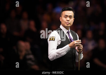 Marco Fu of Hong Kong chalks his cue as he considers a shot to Judd Trump of England in their first round match during the 2017 Dafabet Masters snooke Stock Photo